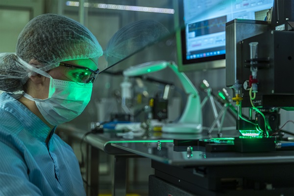 A scientist in a lab environment, wearing protective gear